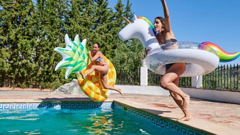 Zwembadliefhebbers springen met opblaasbare zwembandjes in een buitenzwembad